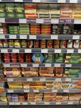 Spinneys Dubai shelves stocked with Italian A brands: John West tuna, Rio Mare, Ortiz sardines, and more canned fish.