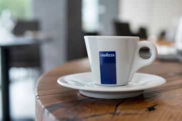 Lavazza espresso cup on a saucer. Coffee drink on a wooden table.